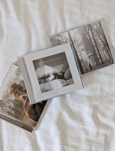 three cd's laying on top of a white sheet covered bed next to each other