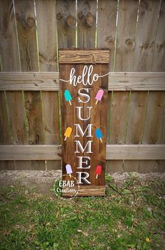 a wooden sign that says hello summer in front of a fence with string lights on it