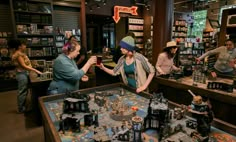 several people are looking at items on display in a store with many shelves full of books