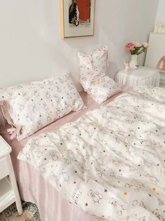 a bed with white sheets and pink comforter in a room next to a nightstand