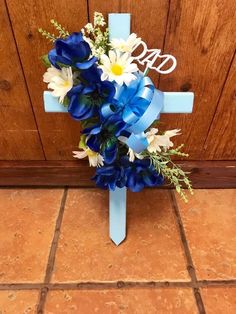 a cross decorated with blue and white flowers on the floor in front of a door