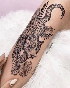 a woman's leg with a leopard and fish tattoo on her arm, next to a white fur rug