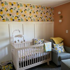 a baby's room with a crib, chair and wallpapered walls