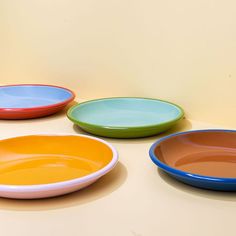 four different colored plates sitting on top of a table