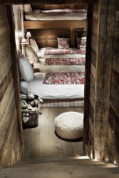 bunk beds are lined up in the corner of a room with wooden walls and flooring