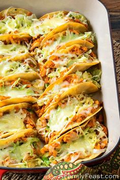 a casserole dish filled with chicken, cheese and tortilla shells covered in shredded lettuce