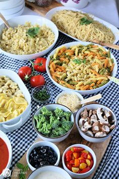 a table topped with bowls filled with pasta and veggies next to other dishes