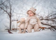 a baby doll sitting on top of a sled next to a stuffed teddy bear