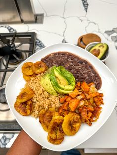 a white plate topped with rice, beans and veggies next to an avocado