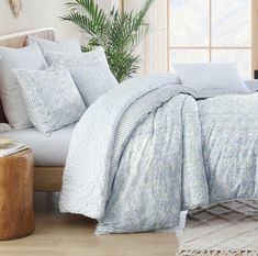 a bed with blue and white comforters in a bedroom next to a window,