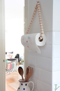 a roll of toilet paper hanging on the wall next to wooden spoons and utensils