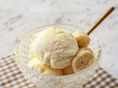 an ice cream sundae with banana slices in it on a checkered tablecloth