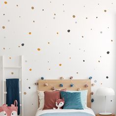 a bed room with a neatly made bed and polka dot wall decals on the walls