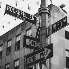 black and white photograph of street signs in front of a building with stars on it