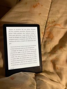 a kindle sitting on top of a bed next to an orange sheeted blanket