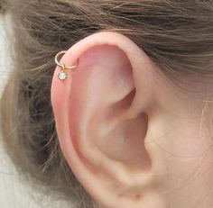 a close up of a person's ear with a single diamond