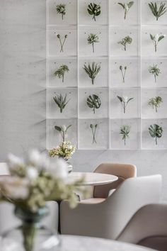 a white table and chairs in front of a wall with plants on it