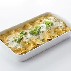 a casserole dish with cheese, green peppers and sauce in it on a white surface