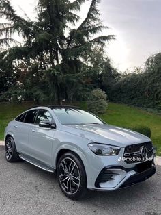 the mercedes gle coupe is parked in front of some trees