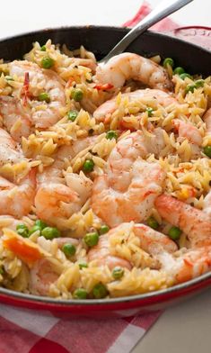 a skillet filled with shrimp and rice on top of a checkered table cloth