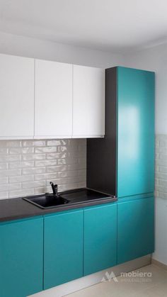 a kitchen with white and blue cabinets and black counter tops in the center, along with a teal sink