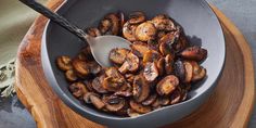 a bowl filled with sliced mushrooms on top of a wooden cutting board next to a spoon