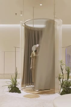 a mannequin is standing in front of a curtained room with plants on the floor