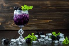 a glass filled with blackberries and ice on top of a table