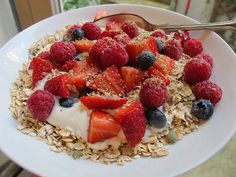 a white bowl filled with granola, berries and yogurt