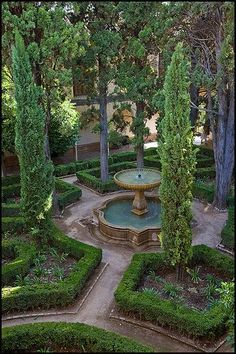 a fountain in the middle of a garden surrounded by trees