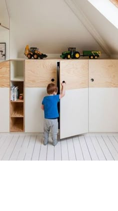 a young boy climbing up the side of a cabinet in a room with white walls