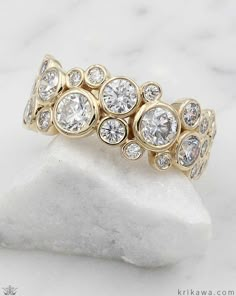 a close up of a gold ring with diamonds on it sitting on a white rock