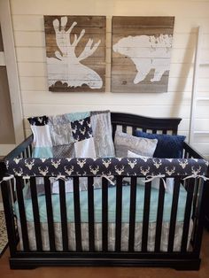 a black crib with blue and white bedding in front of two paintings on the wall