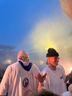 two men with face paint standing in front of an audience at a concert or festival