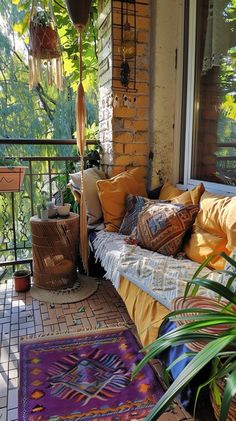 a porch with lots of pillows and rugs on the floor, next to a potted plant