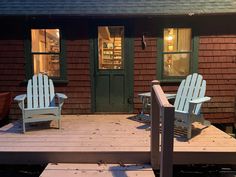 two adiron chairs sitting on top of a wooden deck next to a building with windows