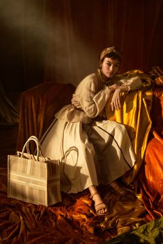 a woman sitting on top of a bed next to a white bag and yellow sheets