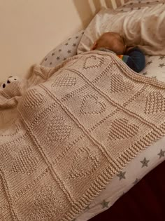 a baby is sleeping in his crocheted bed next to a teddy bear and blanket