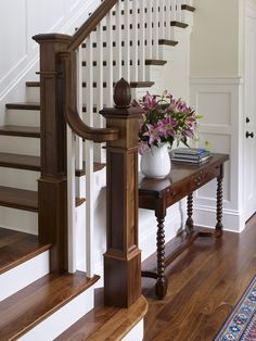 a vase with flowers sitting on a table in front of a stair case next to a banister