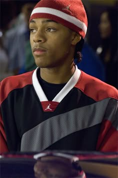 a young man wearing a red and black shirt with a beanie on his head