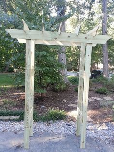 an outdoor wooden arbor with trees in the background