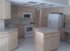 an empty kitchen with white appliances and light wood cabinets