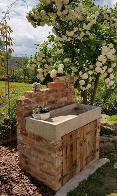 an outdoor kitchen made out of brick and stone blocks with flowers growing on it's side