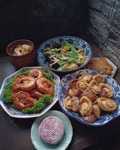 three plates filled with different types of food on top of a wooden table in front of a brick wall