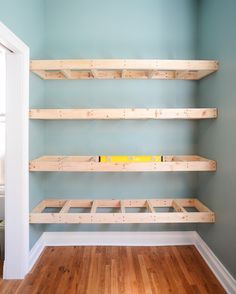 empty shelves in the corner of a room with hard wood flooring and blue walls