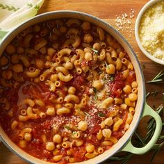 a pot filled with pasta and sauce on top of a wooden table next to other dishes