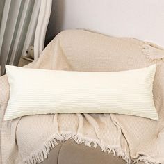 a white pillow sitting on top of a bed next to a chair