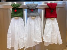 three towels hanging on a rack in front of an oven with hats and scarves