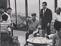 a group of people sitting around a table in a room with glass walls and floor to ceiling windows