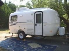 an rv is parked on the side of the road near some trees and a blue towel